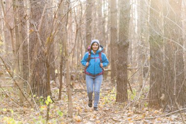 İnsanlar, yürüyüş ve doğa kavramı - giyimli kadın mavi ceketli ormanda yürüyüş