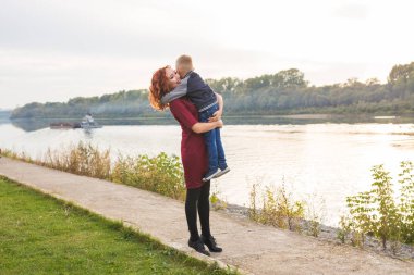 Aile ve çocuk kavramı - oğlu su arka plan üzerinde tutan Kızıl saçlı kadın