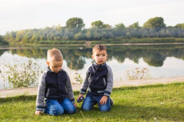 Çocuk ve doğa kavramı - çim üzerinde doğa arka plan üzerinde oturan iki kardeş