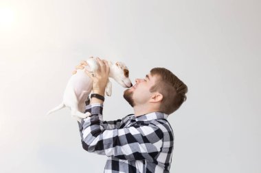 insanlar, Evcil hayvanlar ve hayvanlar kavramı - genç adam tutarak jack russell terrier yavru beyaz arka plan üzerinde