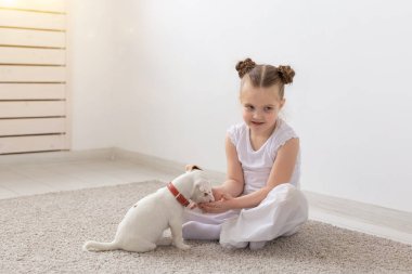 Çocuk, Evcil hayvanlar ve hayvanlar kavramı - küçük kız çocuk pijama ile Jack Russell Terrier köpek yavrusu yerde oynamak