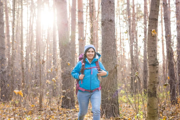 秋の自然な背景の上にバックパックと一緒に歩いている観光客女性の笑って - 冒険、旅行、観光、ハイキング、人々 の概念 — ストック写真