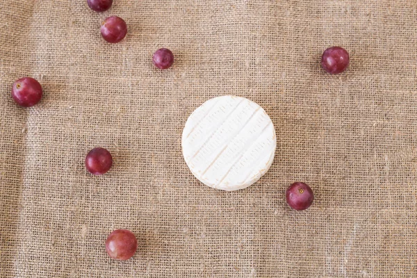 Brie oder Camembert mit Trauben auf rustikalem Hintergrund von oben — Stockfoto
