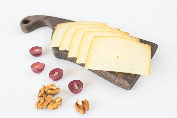 Fresh products. Sliced cheese with grapes and nuts on rustic table.