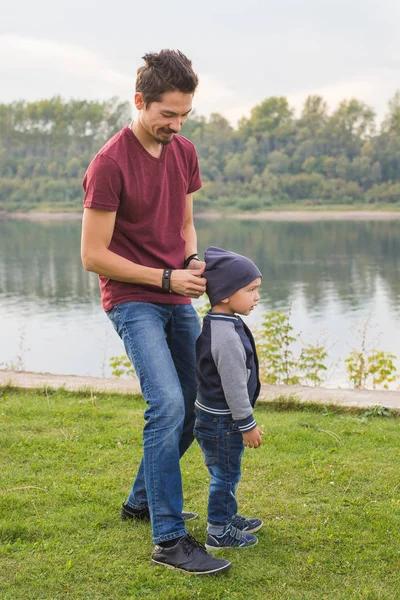 Infancia, concepto familiar - padre jugando con su hijo cerca del lago — Foto de Stock