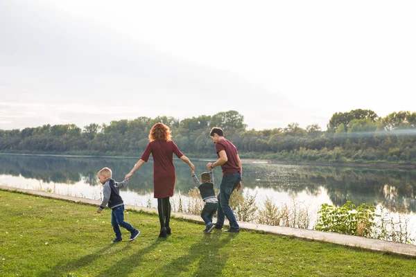 Eltern, Kindheit und Naturkonzept - Familie spielt mit zwei Söhnen am Wasser — Stockfoto