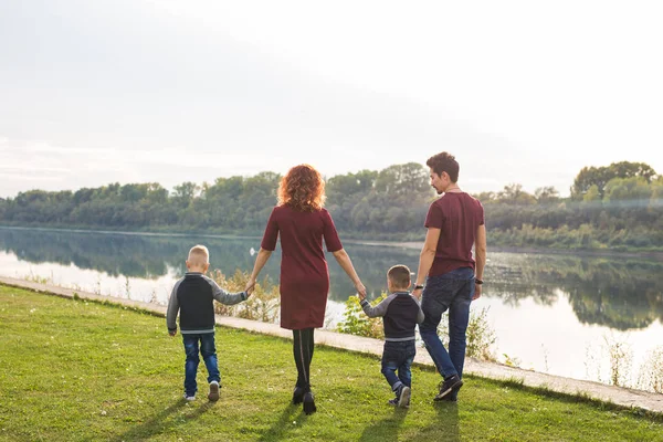 Parent, childhood and nature concept - Family playing with two sons by the water — Stock Photo, Image