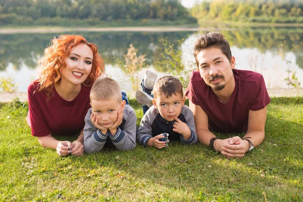 Concepto de la infancia y la naturaleza - Familia con hijos pequeños sentados en la hierba verde — Foto de Stock