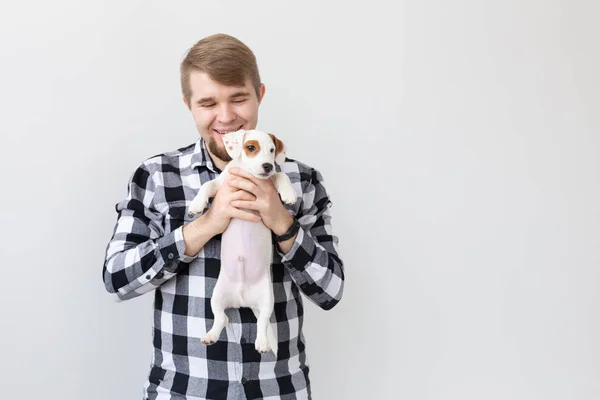 Concepto de personas, mascotas y animales - hombre joven sosteniendo gato russell terrier cachorro sobre fondo blanco con espacio de copia — Foto de Stock