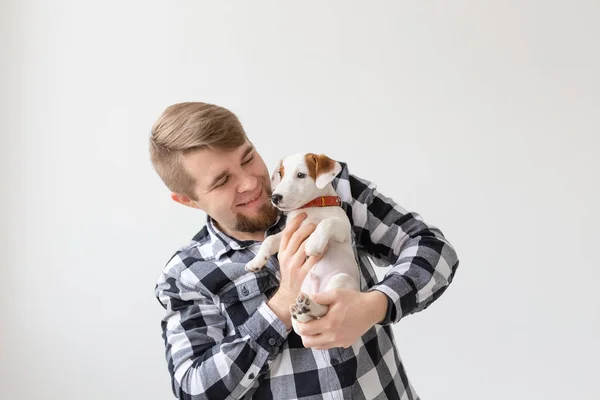 Concepto de personas, mascotas y perros - Hombre sonriente sobre fondo blanco sosteniendo cachorro Jack Russell Terrier — Foto de Stock