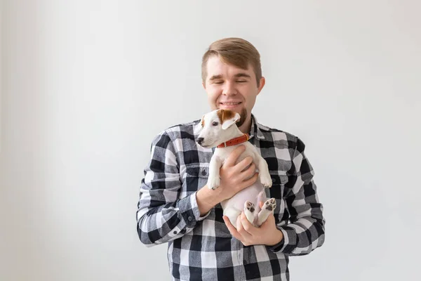 Concepto de personas, mascotas y perros - joven abrazando divertido cachorro Jack Russell Terrier sobre fondo blanco — Foto de Stock