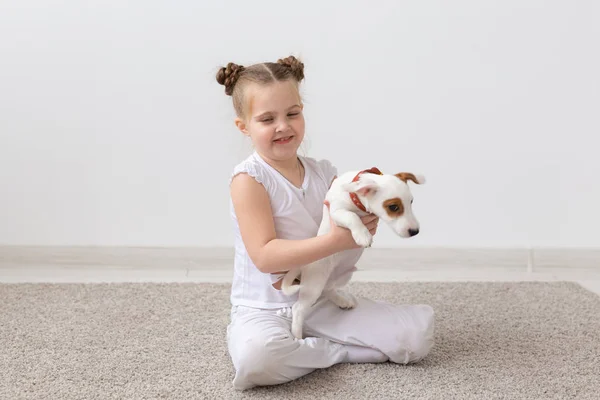 Mascotas, niños y concepto animal - Sonriente niña sentada con el cachorro Jack Russell Terrier — Foto de Stock