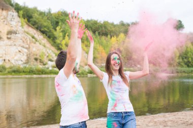 Festival holi, tatil, turizm ve doğa kavramı - çift renkli toz ile oynayan beyaz gömlek giymiş
