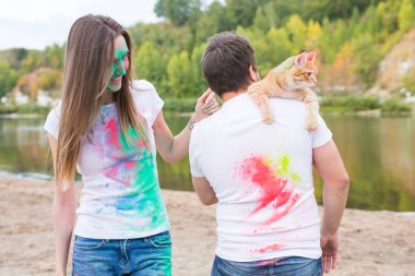 Festival holi, tatil, turizm ve doğa kavramı - çift kedi holding beyaz gömlek giymiş ve renkli tozla kaplı