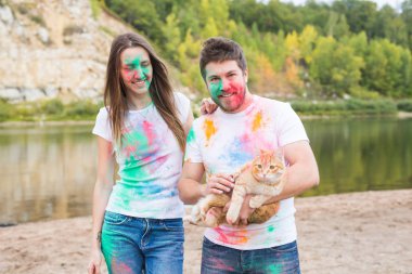 Festival holi, turizm ve doğa kavramı - kadın ve erkek kedi ile portre çok renkli toz kaplı.