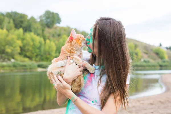 축제 holi, 공휴일, 여름 관광 및 자연 개념-자연 배경 색깔의 먼지에서 고양이 함께 젊은 매력적인 여자 — 스톡 사진