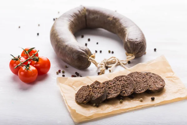 Food, meat and delicious concept - sausages made with horse meat with tomatoes on table — Stock Photo, Image