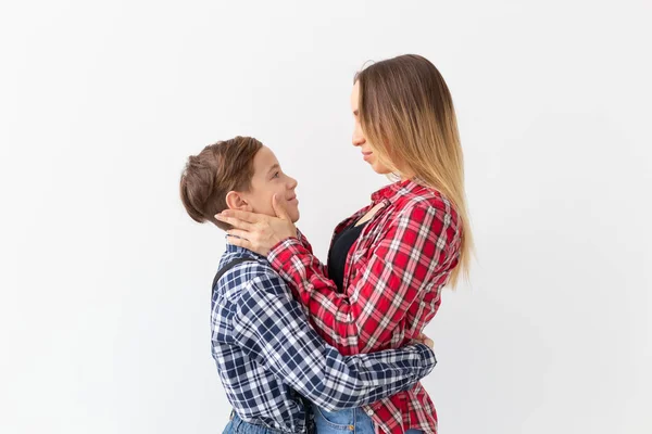 Family, fashion and mother day concept - teen boy hugging his mom on white background — Stock Photo, Image