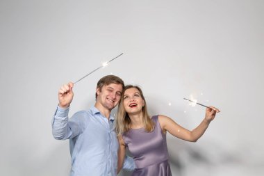 Parti, kutlama, olay ve tatil kavramı - giyinmiş adam mavi gömlek ve mor elbise ambarda giymiş kadın havai fişek sopa