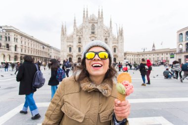 Tatiller, İtalya ve kış konsepti seyahat - genç komik kadın gezgin Milano Duomo Katedrali önünde dondurma dondurma ayakta tutan.