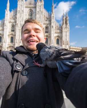 Kış seyahat, tatil ve kuşlar kavramı - yakışıklı erkek turist Milano'da ünlü Duomo Katedrali önünde selfie fotoğraf yapma komik güvercinler ile.