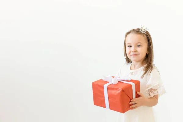 Vacaciones y presenta concepto - Niña sonrisa y la celebración de la caja de regalo roja sobre fondo blanco con espacio de copia — Foto de Stock