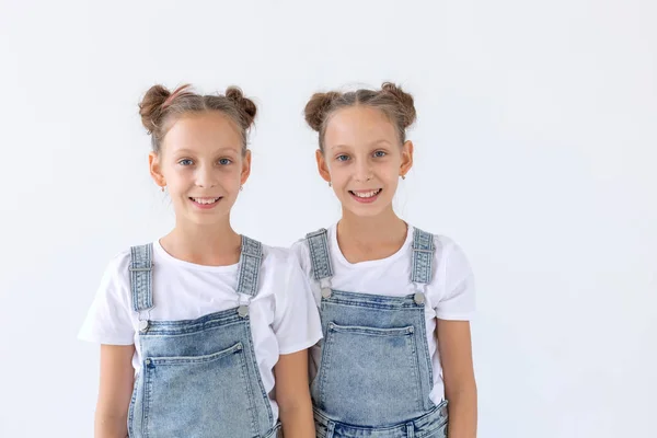 Concepto de familia y amor: dos hermanas gemelas sonrientes abrazándose sobre un fondo blanco — Foto de Stock