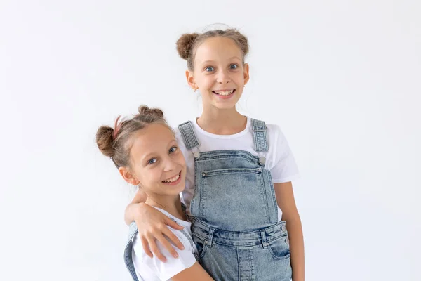 Concepto de familia y amor: dos hermanas gemelas sonrientes abrazándose sobre un fondo blanco — Foto de Stock