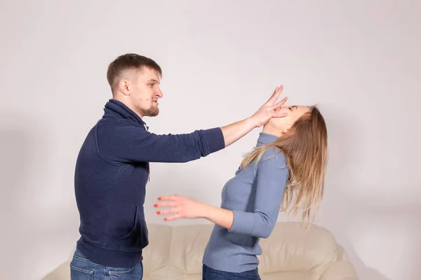 Violencia doméstica y el concepto de abuso: el joven amenaza a su esposa con su puño sobre fondo blanco —  Fotos de Stock