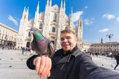Kış seyahat, tatil ve kuşlar kavramı - yakışıklı erkek turist Milano'da ünlü Duomo Katedrali önünde selfie fotoğraf yapma komik güvercinler ile.