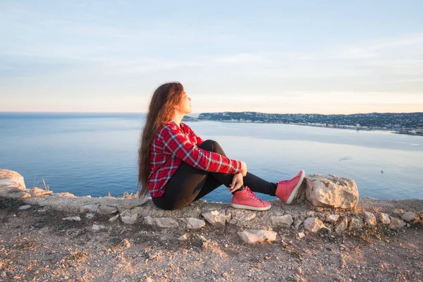 Концепція подорожей, пригод і самотності - дівчина сидить на краю скелі і дивиться на море — стокове фото