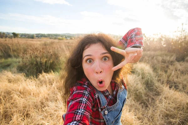 Viajes, vacaciones y concepto de vacaciones - Mujer joven feliz divirtiéndose tomando selfie contra el fondo en el campo —  Fotos de Stock