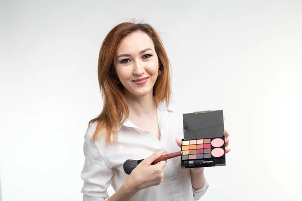 Attraktive Visagistin oder koreanische Visagistin mit einem Make-up-Pinsel und einer Palette von Lidschatten auf weißem Hintergrund — Stockfoto