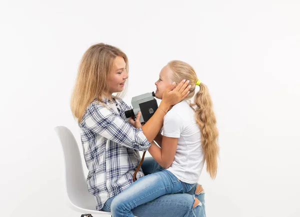 Foto, Fotograf und Retro-Kamera-Konzept - junge Frau und ihre Teenager-Tochter mit Vintage-Kamera auf weißem Hintergrund — Stockfoto