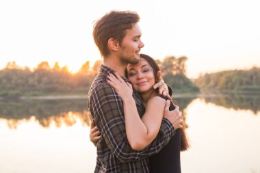 İlişki, aşk ve doğa kavramı - portre çekici kadın ve yakışıklı adam göl arka plan üzerinde sarılma yakından
