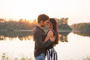İlişki, aşk ve doğa kavramı - portre çekici kadın ve yakışıklı adam göl arka plan üzerinde sarılma yakından