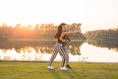 Romantik, sosyal dans ve insanlar kavramı - genç çift bachata günbatımı arka dans