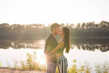 Romantik, aşk, insanlar kavramı - göl kenarında günbatımında sarılma genç çift
