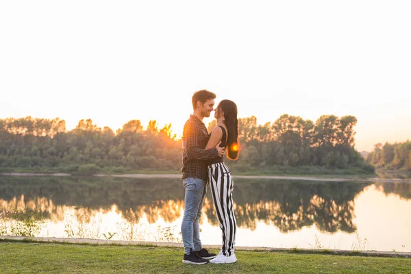 Concetto romantico e popolare - giovane coppia che si abbraccia insieme vicino al fiume o al lago e si gode l'ora legale — Foto Stock