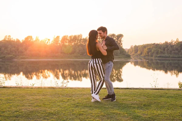 Romantic, social dance and people concept - young couple dancing bachata on the background of sunset — Stock Photo, Image