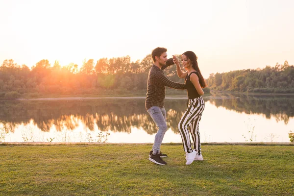 Romântico, dança social, conceito de pessoas - jovem casal bachata dançando perto do lago em dia ensolarado — Fotografia de Stock