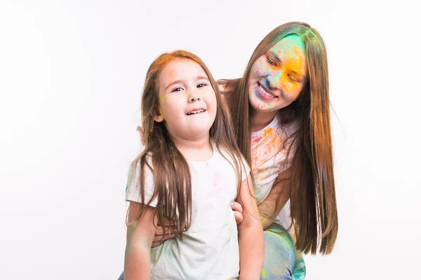 Familj, festival av holi och helgdagar koncept - kvinna och lilla leende flicka täckt med färgglada puder över vit bakgrund — Stockfoto