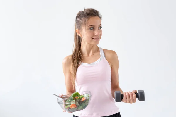 Estilo de vida são, conceito de pessoas - uma chapa de salada em uma mão e halteres em outra mão. Sorriso e terno fitness — Fotografia de Stock