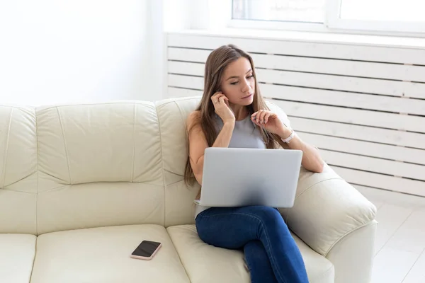 Concetto di freelance e persone - Giovane donna seduta su un divano e che lavora al computer portatile — Foto Stock