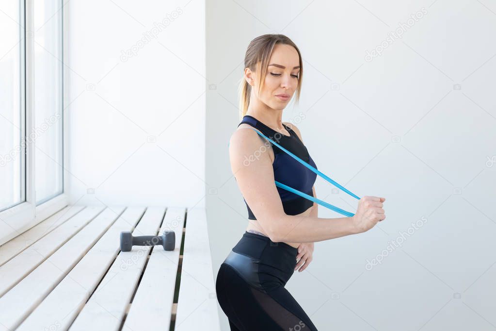 People, healthy and sport concept - Fit woman In sports clothes squatting with band