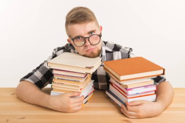 İnsanlar, sınav ve eğitim kavramı - bitkin ve yorgun öğrenci ile pek çok kitap ahşap masada oturan ekose gömlek giymiş