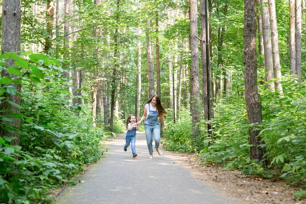 Familie, natuur, kinderen concept - moeder en haar dochtertje tijd met elkaar doorbrengen op een wandeling in het park in de zomer — Stockfoto