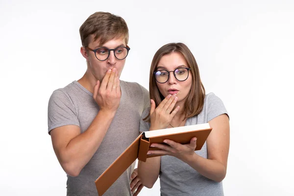 Nerds, Studium, Menschen-Konzept - ein paar Leute schauen sich das Buch an und wirken überrascht — Stockfoto