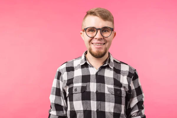 Ritratto di un uomo barbuto sorridente con gli occhiali che guarda la macchina fotografica isolata su sfondo rosa — Foto Stock