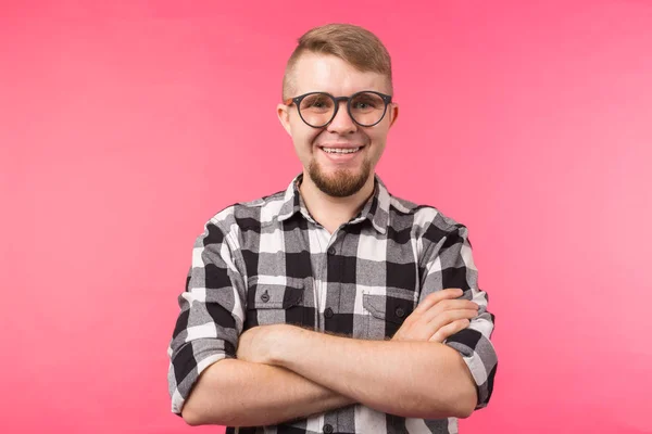 Muotokuva hymyilevästä parrakkaasta miehestä silmälaseissa katselemassa kameraa, joka on eristetty vaaleanpunaisella taustalla — kuvapankkivalokuva